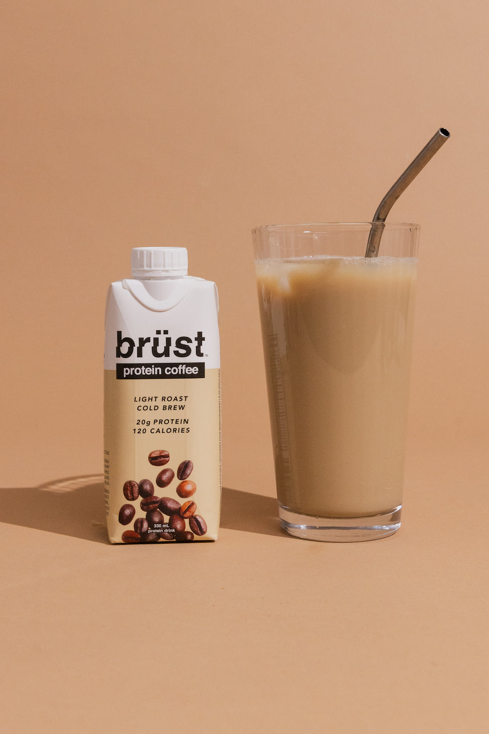 brüst original light roast protein cold brew coffee bottle beside a glass of iced coffee