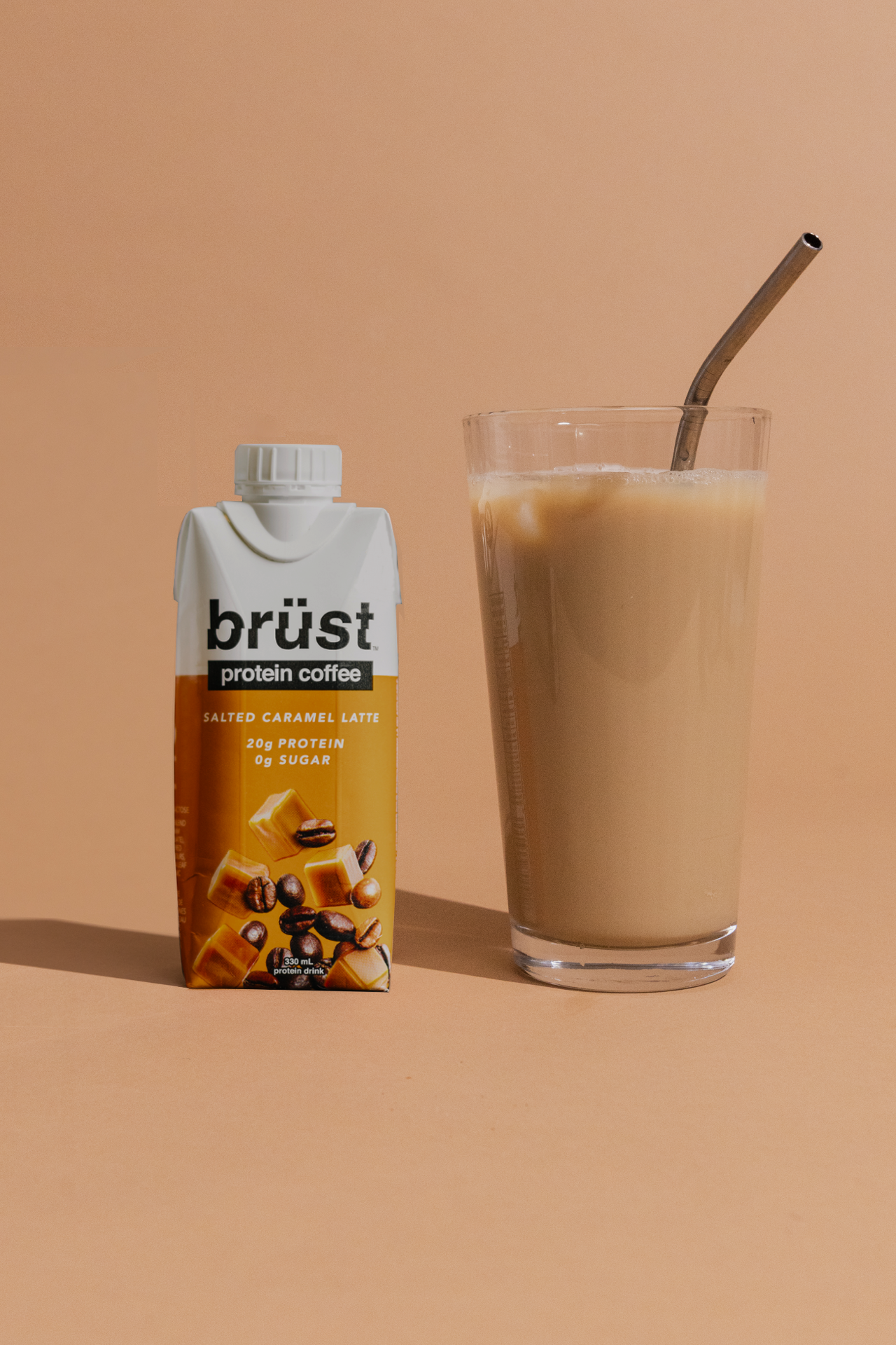 brüst salted caramel latte protein cold brew coffee bottle beside a glass of iced coffee