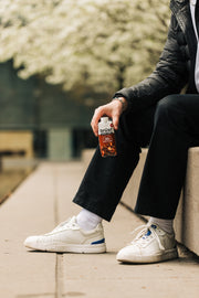person holding a brüst chocolate hazelnut latte protein coffee bottle while sitting outdoors