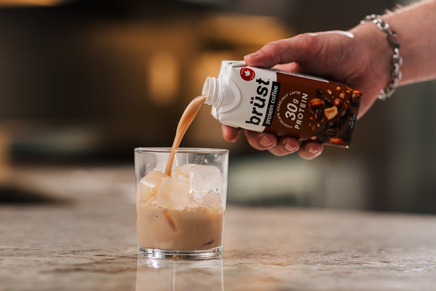 pouring brüst chocolate hazelnut protein cold brew coffee over ice in a glass