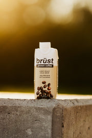 brüst original light roast protein cold brew coffee bottle on a concrete ledge outdoors