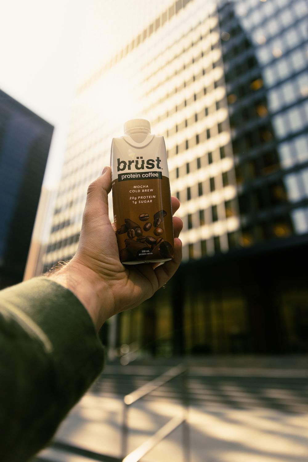 hand holding a brüst mocha protein cold brew coffee bottle in the city