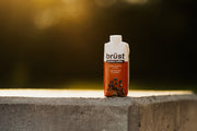 brüst pumpkin spice latte protein coffee bottle on a concrete ledge outdoors